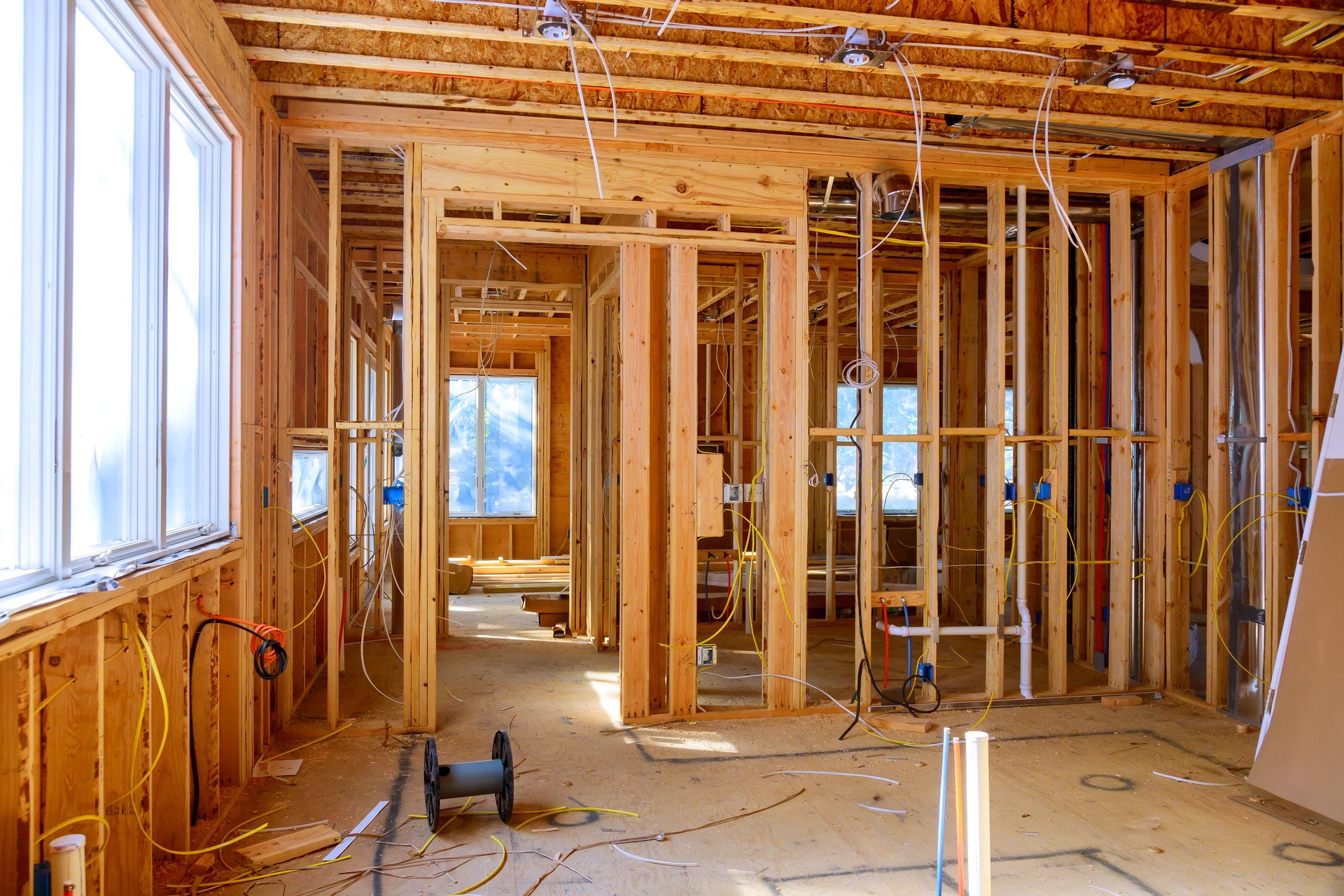 Worker installs electrical wires, insulation, and ceiling light before plasterboard